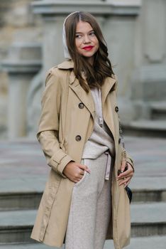 Portrait of fashionable women in beige sports suit and trench coat posing. street look fashion