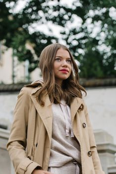 Portrait of fashionable women in beige sports suit and trench coat posing. street look fashion