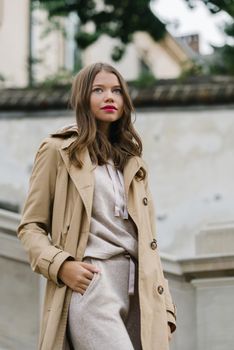 Portrait of fashionable women in beige sports suit and trench coat posing. street look fashion