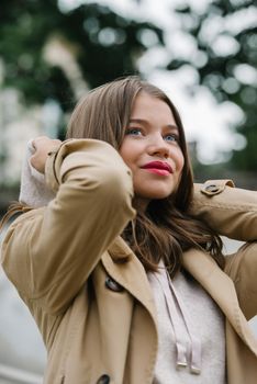 Portrait of fashionable women in beige sports suit and trench coat posing. street look fashion