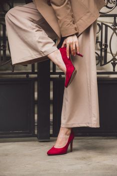 Close up portrait of young beautiful woman with long brunette curly hair posing against building background. woman wearing a white blouse and beige pants and a jacket