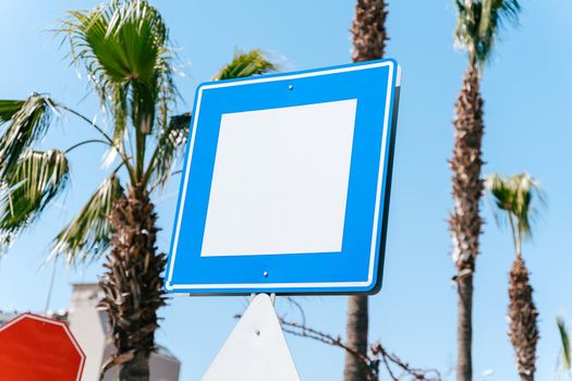 Blank empty copy space blue and white street sign with blue sky and palm trees in background. Mockup signpost.