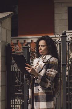 Female real estate agent with clipboard outdoors. woman wearing a white blouse and a checkered coat