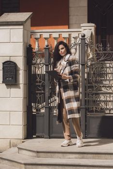 Female real estate agent with clipboard outdoors. woman wearing a white blouse and a checkered coat