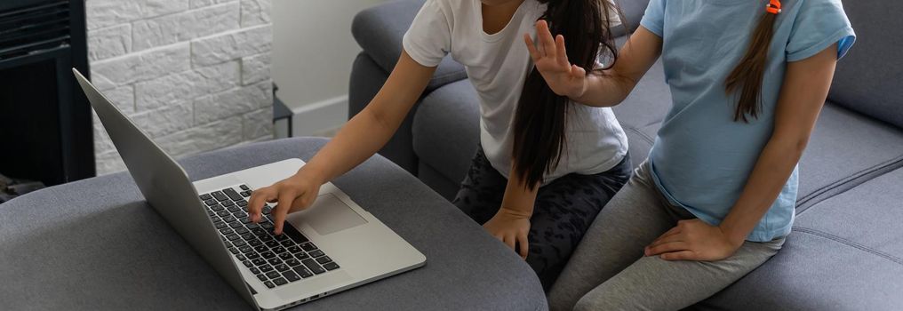 Two girls working on laptop, smiling and older sister help younger.