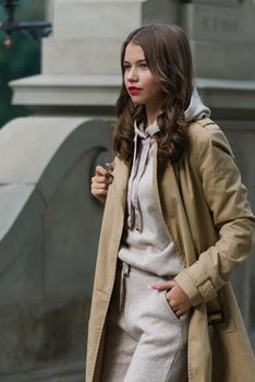 Portrait of fashionable women in beige sports suit and trench coat posing. street look fashion