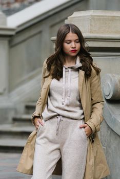 Portrait of fashionable women in beige sports suit and trench coat posing. street look fashion