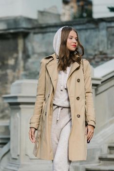 Portrait of fashionable women in beige sports suit and trench coat posing. street look fashion