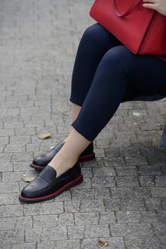 Female fashion concept. Womans legs in a black shoes with red line City lifestyle