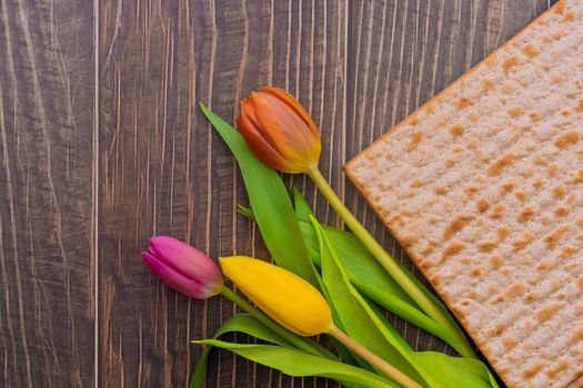 Passover Jewish holiday on flowers and matzah the wood table