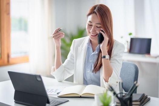 Asian Business woman working to analyze technical price graph and indicator with business team talking by cell phone. account or saving money or insurance concept