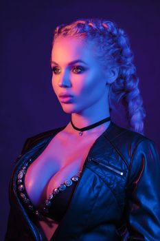Portrait of seductive young European woman surrounded by evening neon lights medium close-up. Beautiful sexy female fashion model with modern hairstyle isolated at studio black background