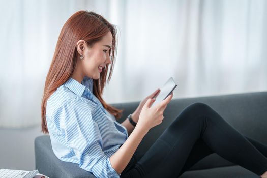 Woman enjoy with content streaming movies or social media application on digital tablet sitting on sofa at home