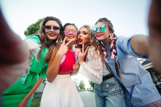 Four fashionable and beautiful best girlfriends in glasses, posing do general self for social networks, lifestyle, spend time fun. Women in sunglasses Holidays in the city