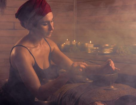 A woman performs a Tibetan ritual with sound bells. The concept of therapy.
