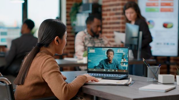 Asian woman attending online videocall meeting on laptop, using remote videoconference for communication with businessman. Employee having conversation on video teleconference chat.