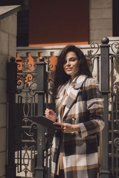 Female real estate agent with clipboard outdoors. woman wearing a white blouse and a checkered coat