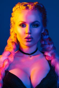 Portrait of seductive young European woman surrounded by evening neon lights medium close-up. Beautiful sexy female fashion model with modern hairstyle isolated at studio black background