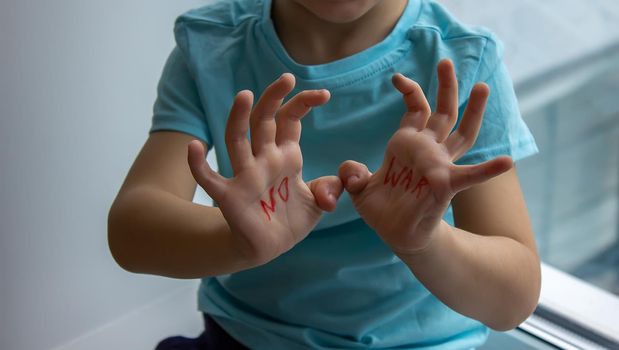 a little boy has an inscription on his palms no to war. selective focus