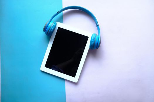 Audio book concept. Headphones and digital tablet on table .