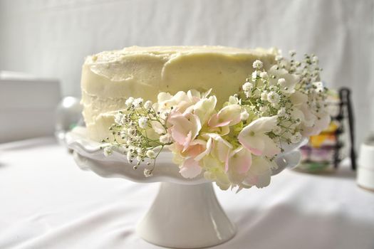 White Buttercream Wedding Cake on Stand Decorated With Hydrangeas and Baby's Breath Flowers. High quality photo