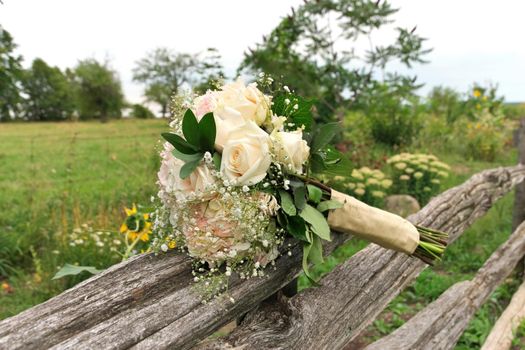 Bouquet of White and Pink Roses with Babys Breath on Split Rail Fence in Farm Field in Summer