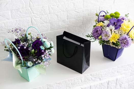 black empty paper bags and bouquets. Blank wall.