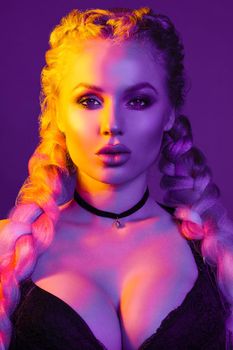 Portrait of seductive young European woman surrounded by evening neon lights medium close-up. Beautiful sexy female fashion model with modern hairstyle isolated at studio black background