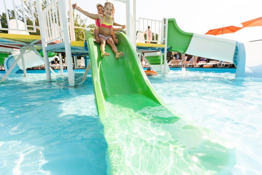 two girls splash in an outdoors swimming pool in summer. Happy children, sister playing, enjoying sunny weather in public pool.