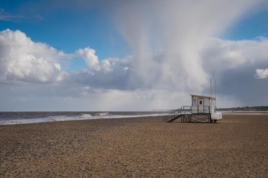 Hail storm passing over lifeguard hut on a deserted beach on a cold windy winters day, Gorleston-on-Sea, near Great Yarmouth, Norfolk, UK