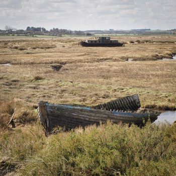 Abandoned derelict boat wrecks on the expansive salt marshes, Blakeney National Nature Reserve, Norfolk, UK