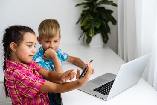 Cute children use laptop for education, online study, home studying, Boy and Girl have homework at distance learning. Lifestyle concept for home schooling