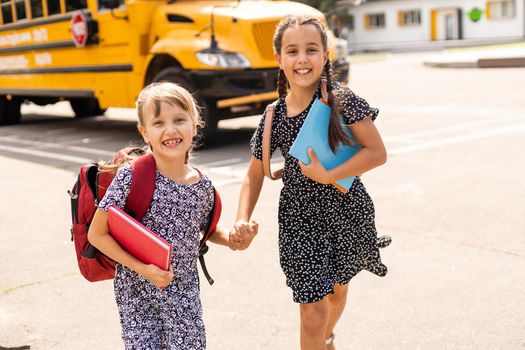 Portrait of two girls with school bags after lesson in school.