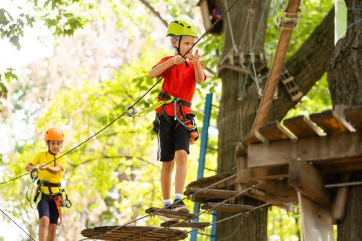 Adventure climbing high wire park - little boy on course in mountain helmet and safety equipment.
