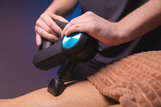 Professional massage with a percussion back massager for a man. Working as a percussion massager.