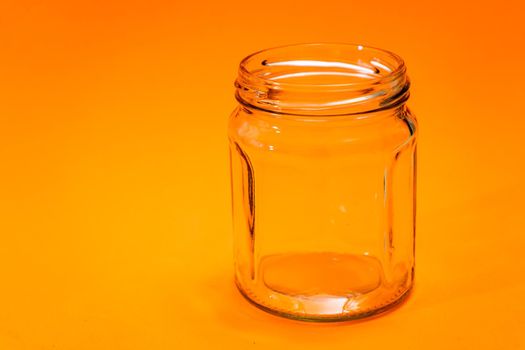 Empty hexagonal glass flask isolated on orange bottom.