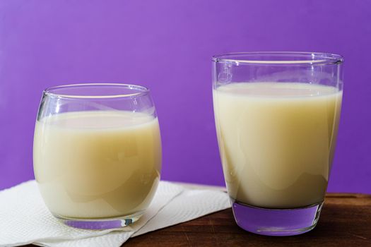 Two glasses of milk of different shape and volume on a wooden board on a table. Healthy Drink. close up