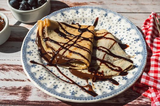 Plate two exquisite homemade pancakes or crepes filled with almond cream and chocolate with chocolate threads covering.