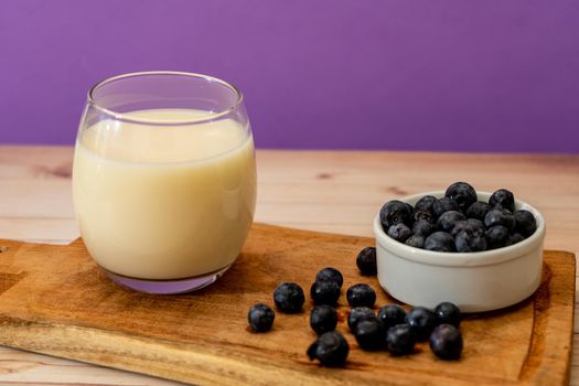 High view of a glass of milk next to some blueberries in a modern, stripped-down setting.