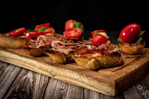 Arrangement of a selection of different tapas or bruschettas on a wooden board. Mediterranean food concept. High view.