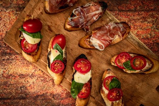 Arrangement of a selection of different tapas or bruschettas on a wooden board. Mediterranean food concept. Top View