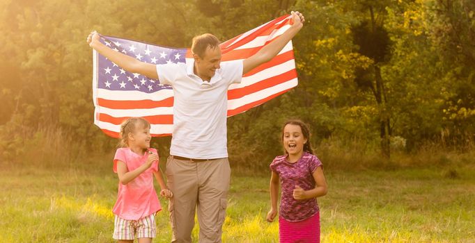 happy family with the flag of america USA at sunset outdoors.