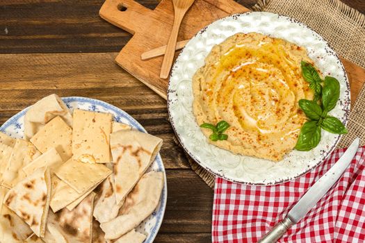 Aerial view of a plate of homemade hummus with pita bread and crackers. Fresh, healthy and natural food concept.