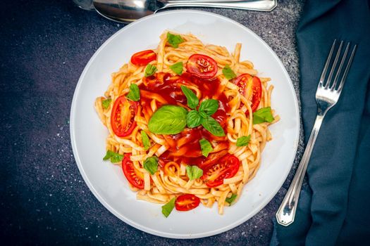 Top view of a plate of spaghetti pasta with a delicious homemade tomato sauce with basil leaves. Natural and homemade food concept.