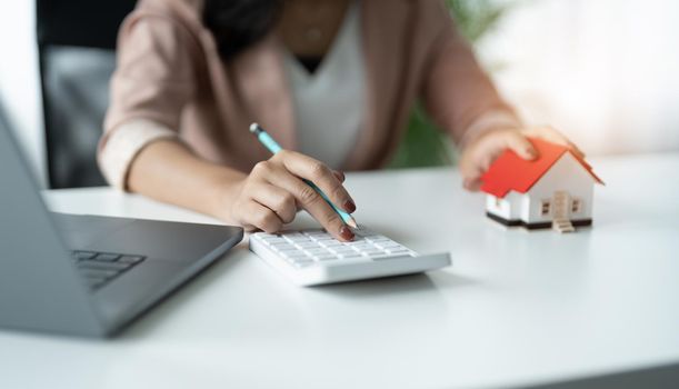 Hand of Business woman calculating interest, taxes and profits to invest in real estate and home buying.