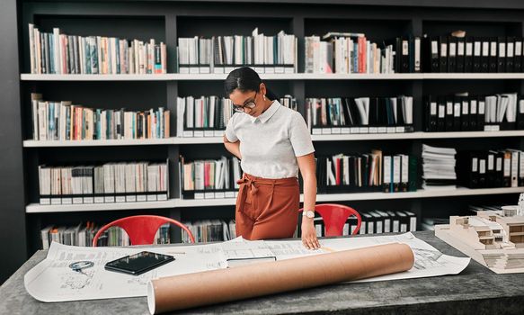 Cropped shot of an attractive young female architect working with blueprints in a modern office.