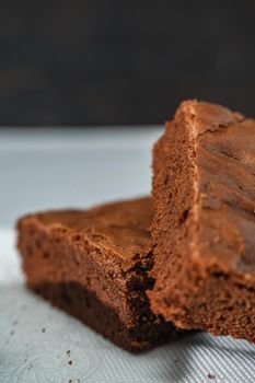 A cubes of chocolate brownies on a white plate on a marble table. Close up shot. vertical orientation.