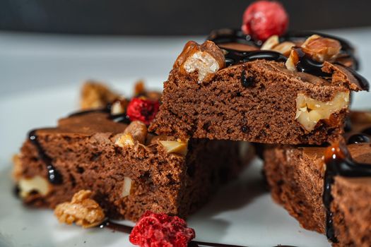 Close-up of homemade chocolate brownies squares with walnut pieces, chocolate strands and granola. Natural, healthy food concept.