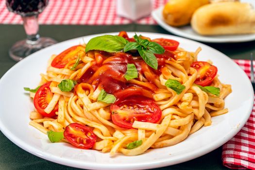 High view of a plate of spaghetti pasta with a delicious tomato sauce with homemade basil leaves. Close up. Homemade and natural food concept.