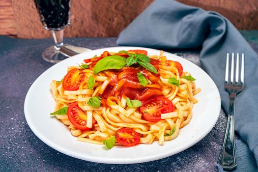 High view of a plate of spaghetti pasta with a delicious tomato sauce with homemade basil leaves. Homemade and natural food concept.